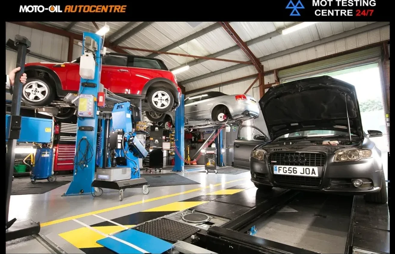 Inside the Moto-Oil Autocentre workshop on Benson Road, Poole — cars raised on the two-post ramps beside the MOT testing bay